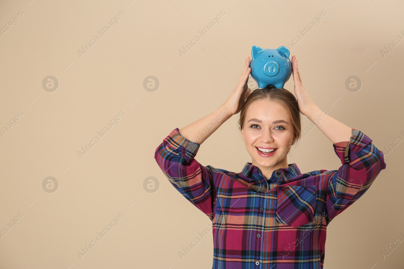 Photo of Happy young woman with piggy bank and space for text on color background. Money saving