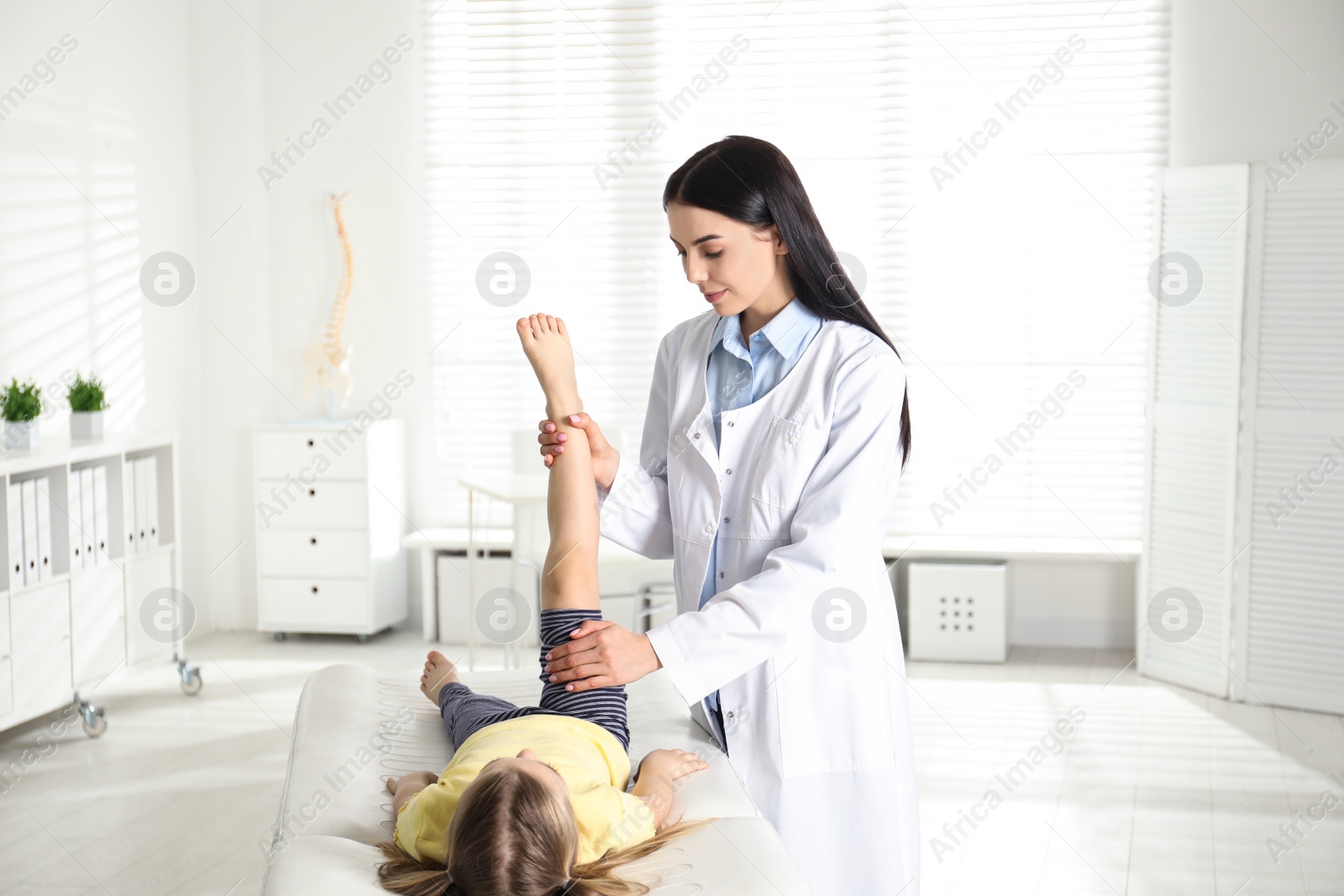 Photo of Professional orthopedist examining little patient's leg in clinic