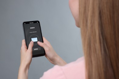 Image of Got new message. Woman using smartphone on grey background, closeup