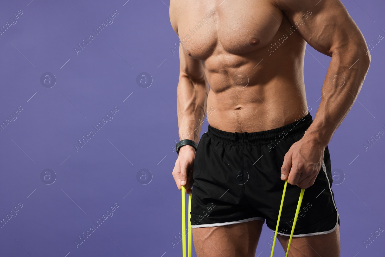 Photo of Muscular man exercising with elastic resistance band on purple background, closeup. Space for text