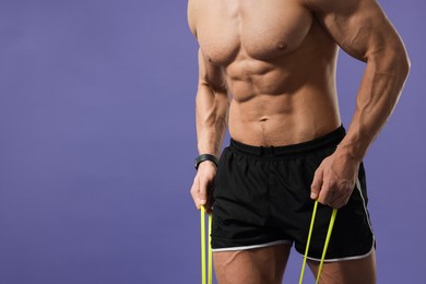 Muscular man exercising with elastic resistance band on purple background, closeup. Space for text