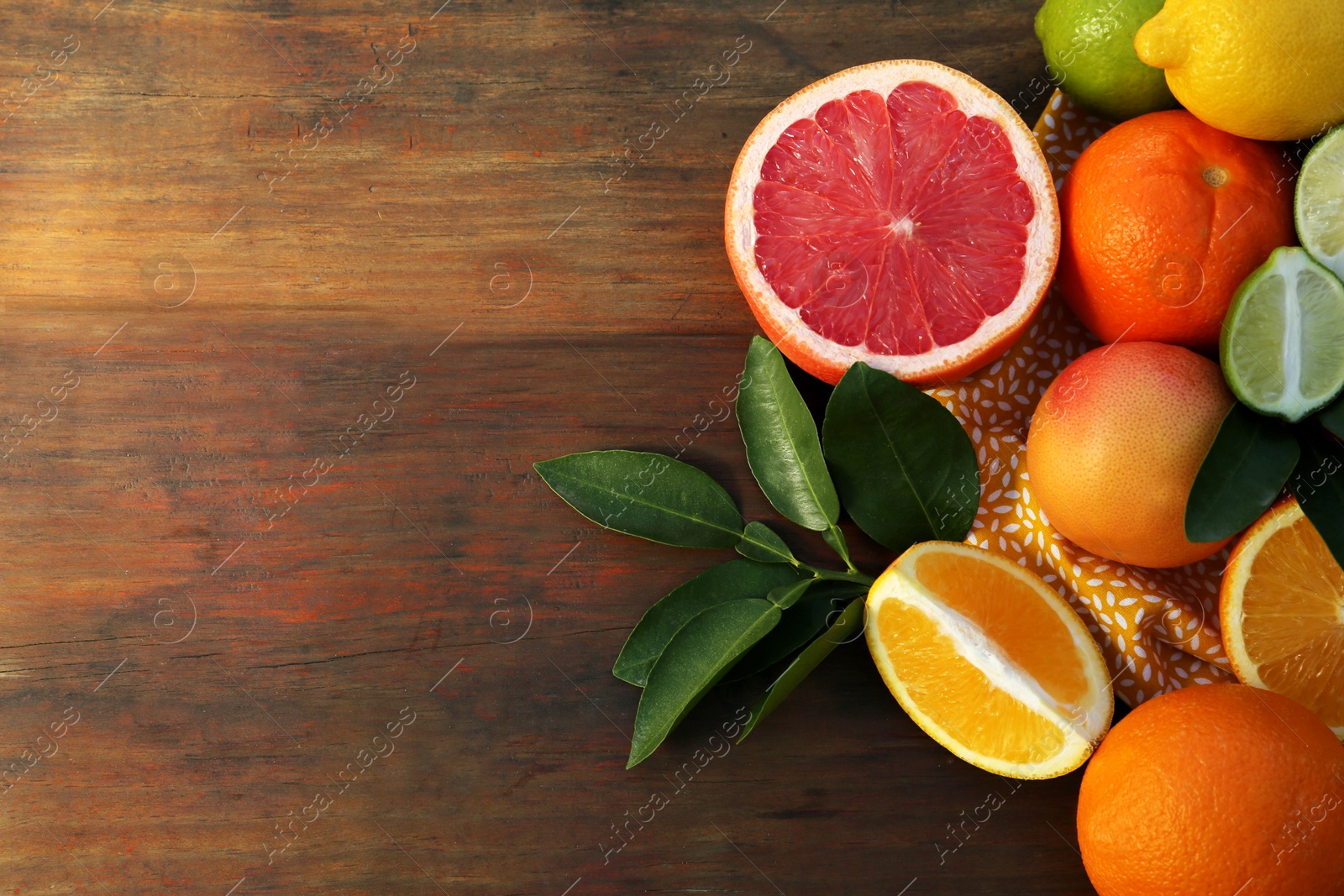Photo of Different citrus fruits and leaves on wooden table, flat lay. Space for text