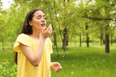 Photo of Young woman suffering from seasonal allergy outdoors, space for text