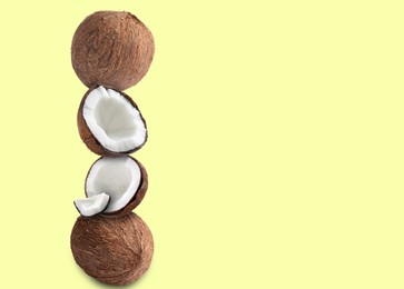 Image of Stack of fresh coconuts on pale light yellow background. Space for text