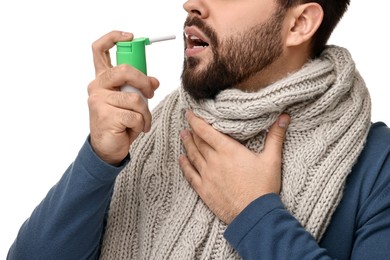 Young man with scarf using throat spray on white background, closeup