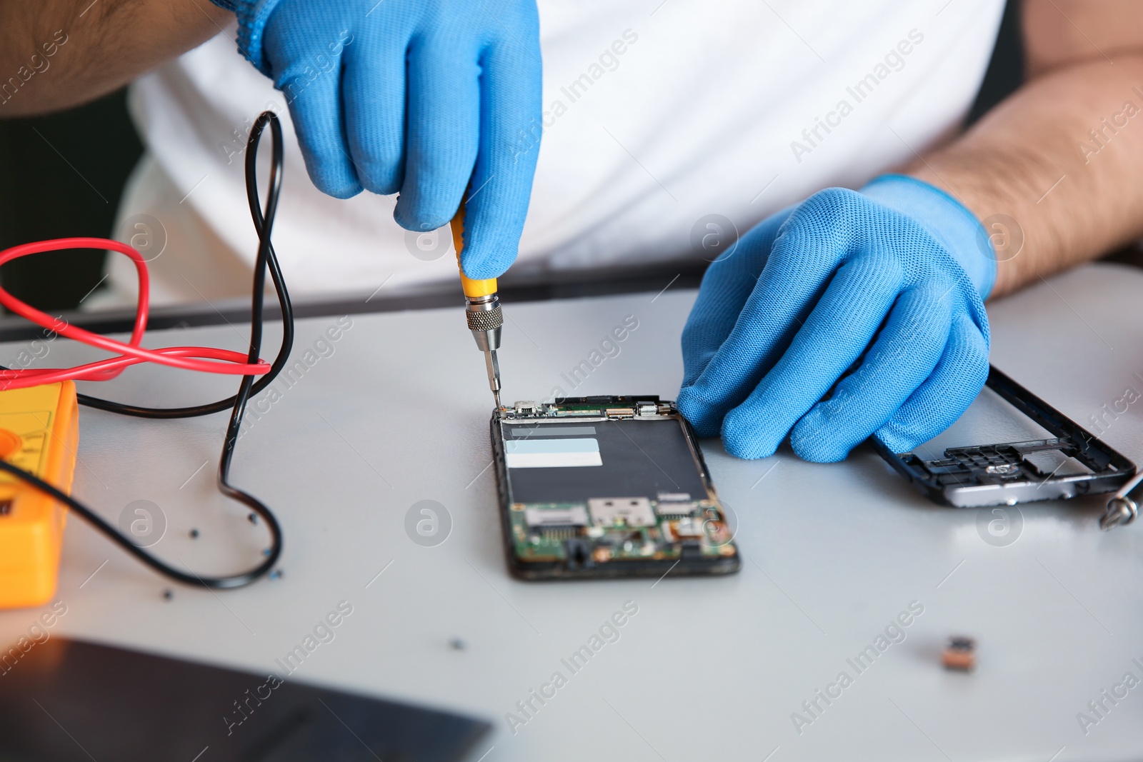 Photo of Technician repairing mobile phone at table, closeup