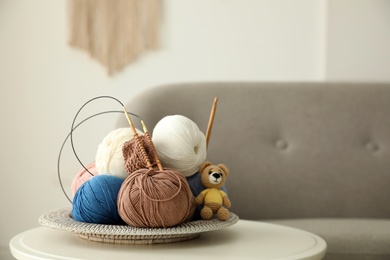 Photo of Toy bear, clews with needles and crochet on table. Engaging in hobby