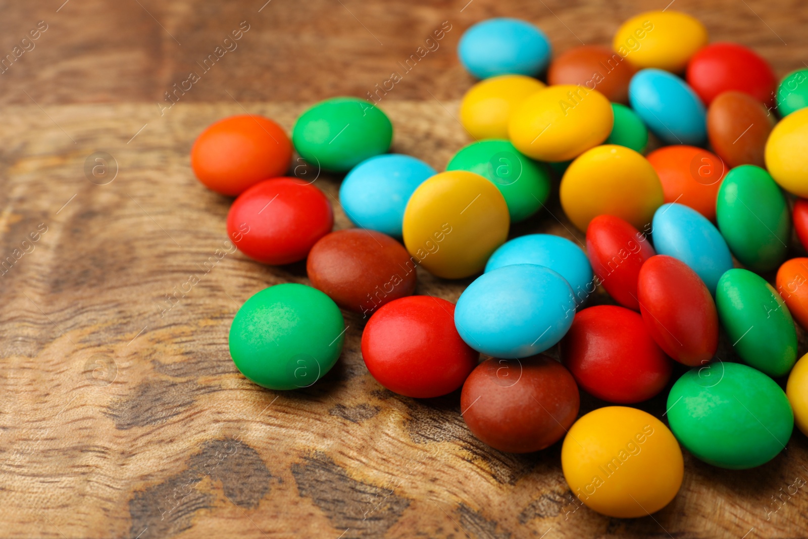 Photo of Tasty colorful candies on wooden table, closeup