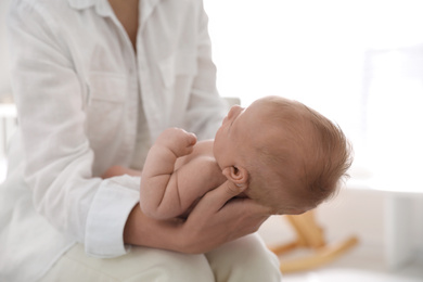 Mother holding her little baby in bedroom