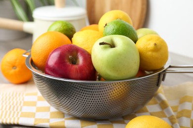 Photo of Metal colander with different fruits on table, closeup