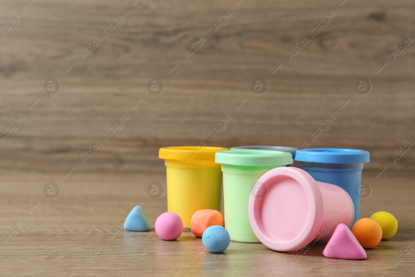 Photo of Different color play dough on wooden table. Space for text