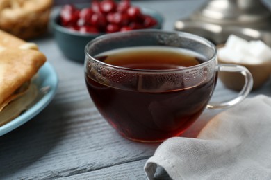 Photo of Glass cup of aromatic tea on light blue wooden table, closeup