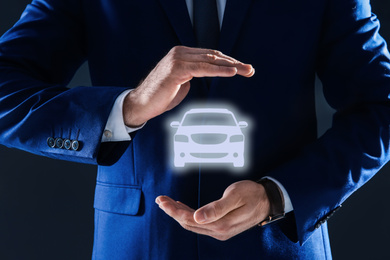 Image of Man demonstrating image of auto on dark background, closeup. Car insurance