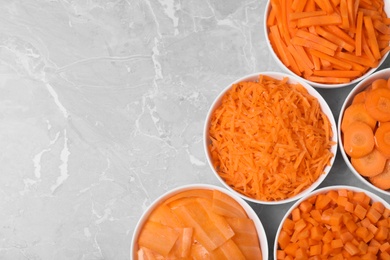 Photo of Flat lay composition with bowls of differently cut carrots on marble background. Space for text