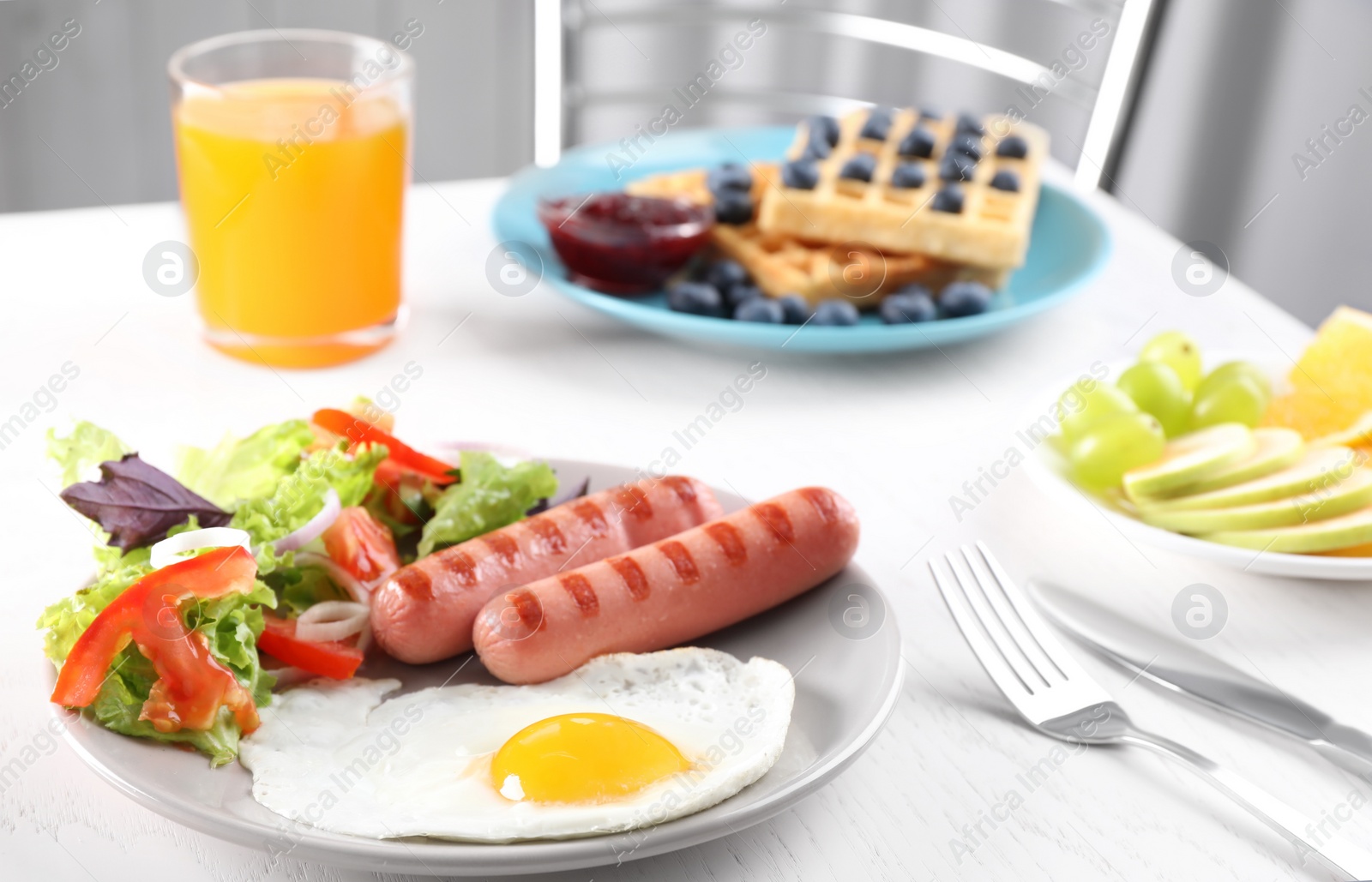 Photo of Delicious breakfast with fried egg and sausages served on white table, closeup