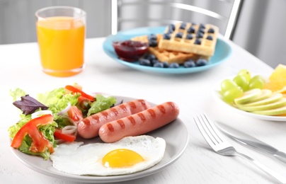 Delicious breakfast with fried egg and sausages served on white table, closeup