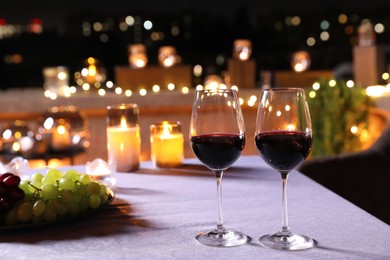 Glasses of red wine on table against blurred cityscape. Modern outdoor terrace