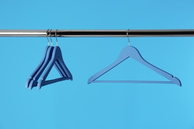 Photo of Metal rack with clothes hangers on color background