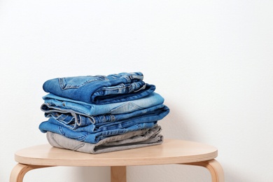 Stack of different jeans on table against white background. Space for text