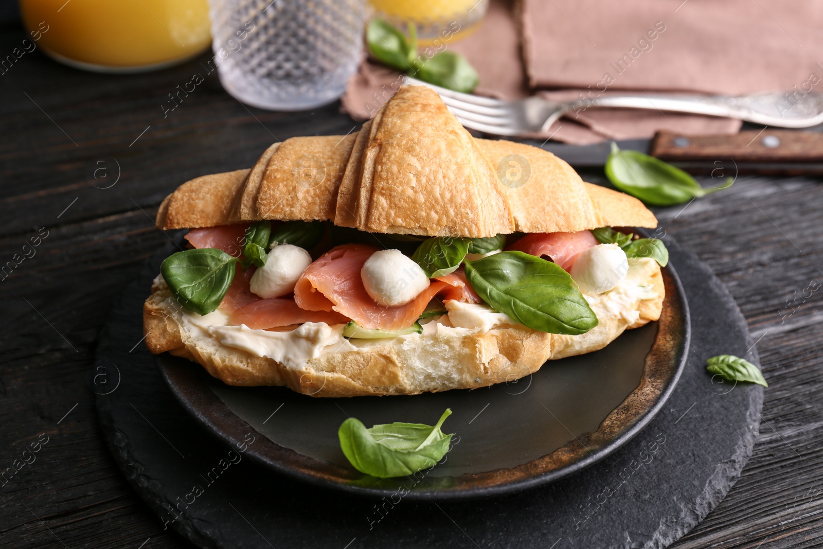 Photo of Tasty croissant sandwich with salmon on table