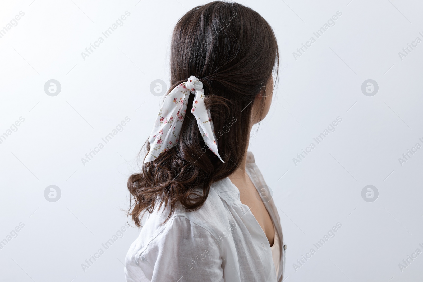 Photo of Young woman with stylish bandana on light background, back view