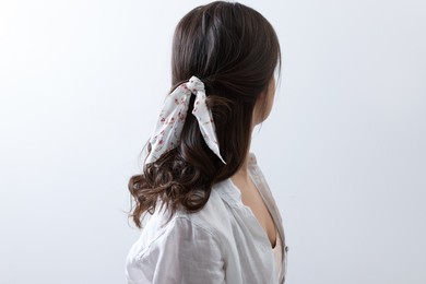 Photo of Young woman with stylish bandana on light background, back view