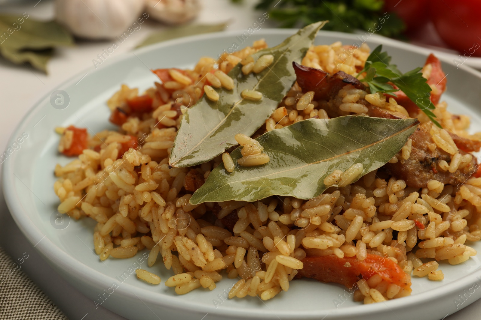 Photo of Delicious pilaf and bay leaves on plate, closeup