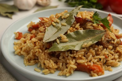 Delicious pilaf and bay leaves on plate, closeup