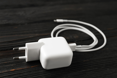 White charging cable and adapter on black wooden table