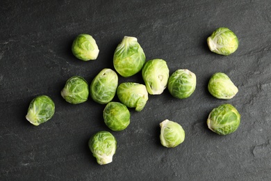 Photo of Fresh Brussels sprouts on black slate table, flat lay