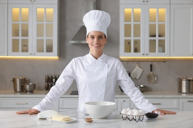 Portrait of professional chef near table with ingredients in kitchen