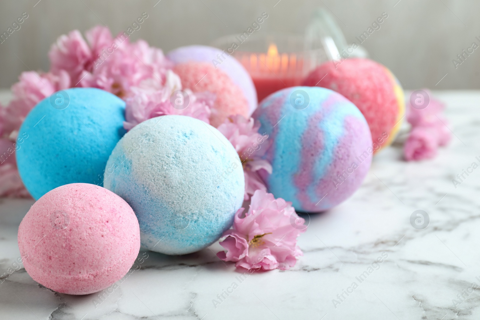 Photo of Fragrant bath bombs and sakura flowers on white marble table