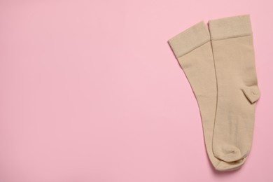 Photo of Pair of new beige socks on pink background, flat lay. Space for text