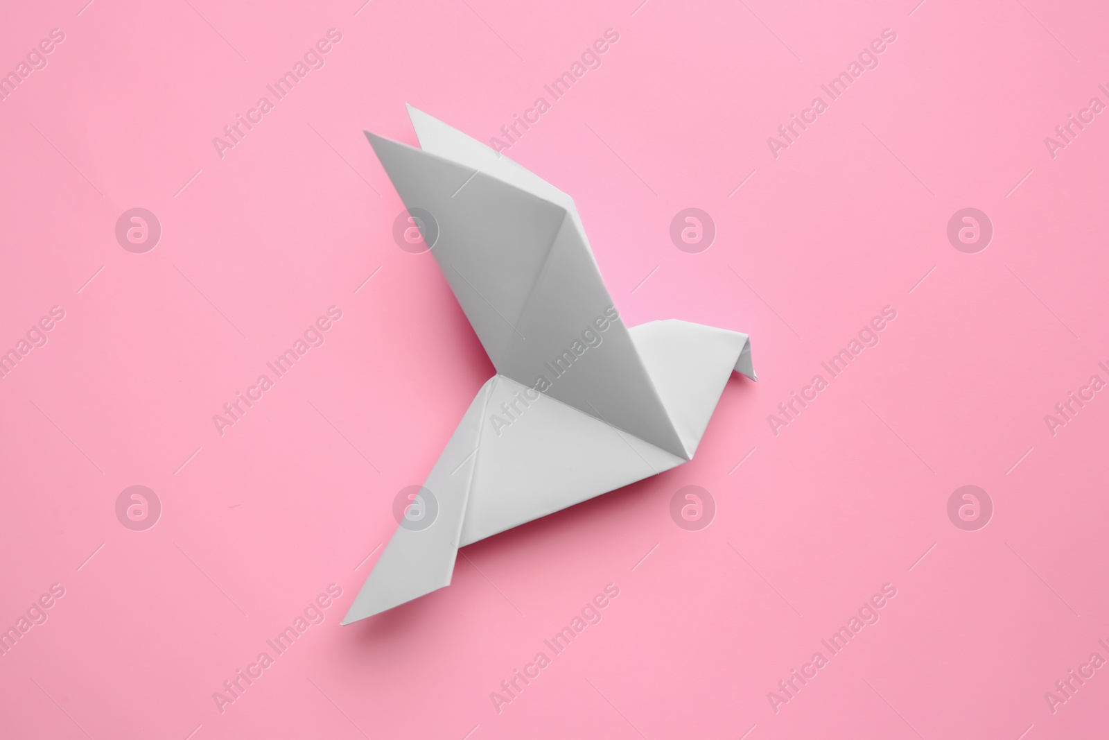 Photo of Beautiful origami bird on pink background, flat lay