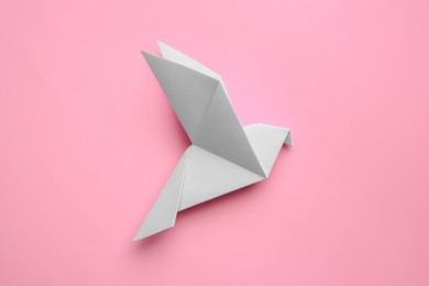 Photo of Beautiful origami bird on pink background, flat lay