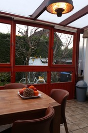 Photo of Wooden table with fruits and stylish chairs on terrace