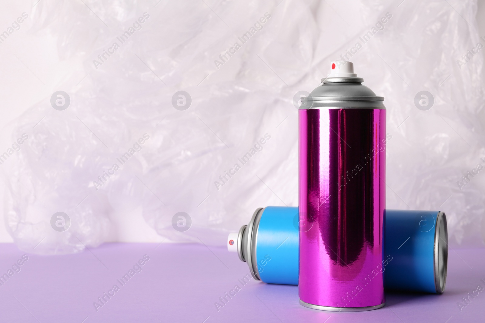 Photo of Cans of different spray paints on color background. Space for text