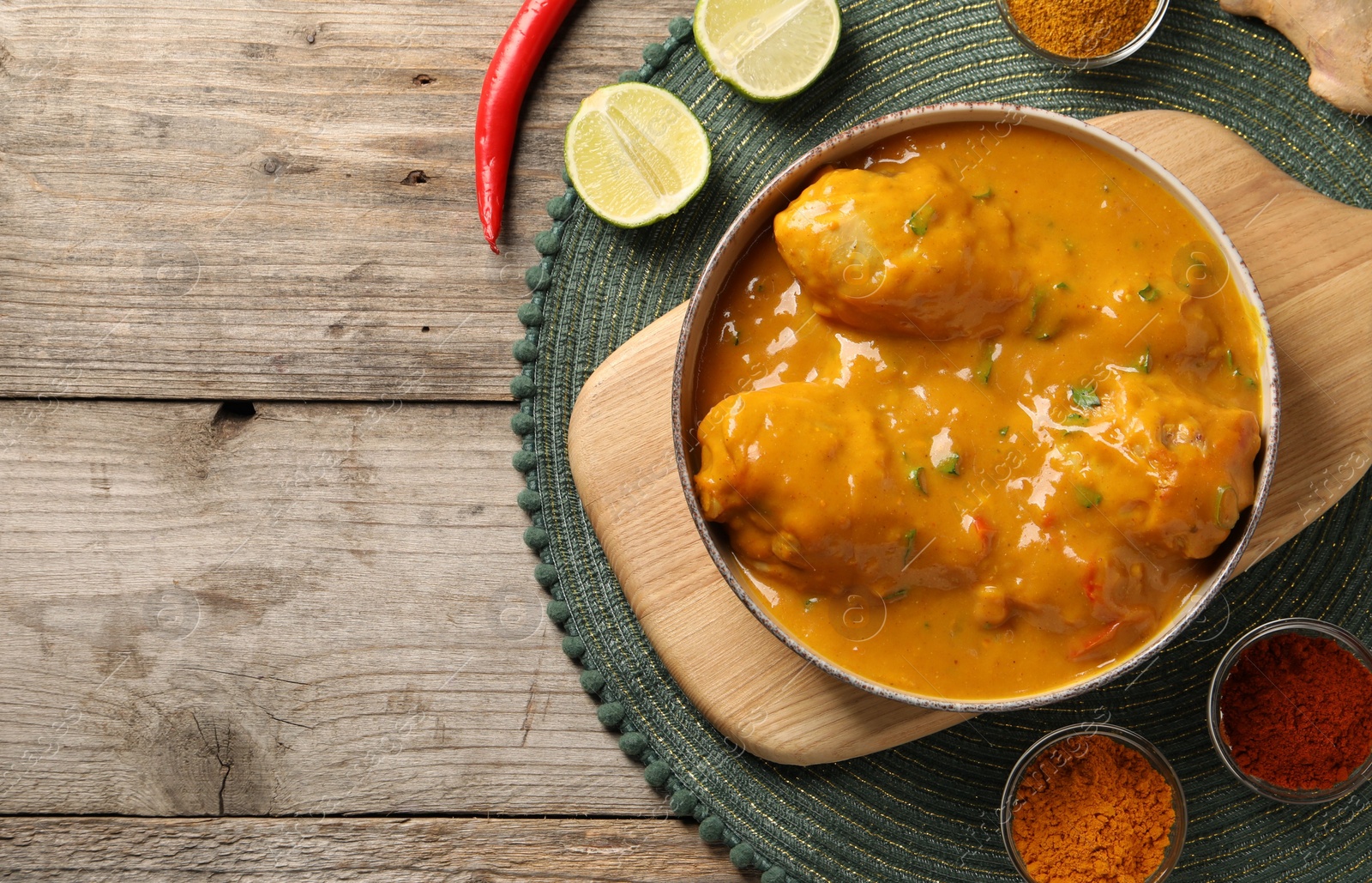 Photo of Tasty chicken curry and ingredients on wooden table, flat lay. Space for text