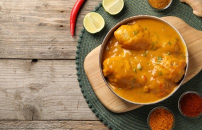 Tasty chicken curry and ingredients on wooden table, flat lay. Space for text