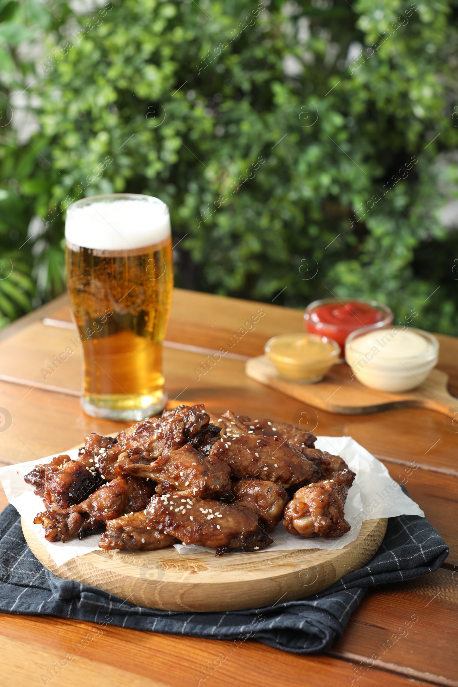 Photo of Tasty roasted chicken wings served with beer on wooden table