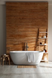 Bathroom interior with white tub and decor near wooden wall