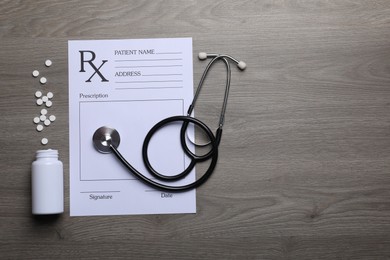 Photo of Medical prescription form, stethoscope and pills on wooden table, flat lay. Space for text