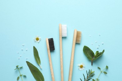 Photo of Bamboo toothbrushes, beautiful chamomile flowers, sea salt and herbs on turquoise background, flat lay