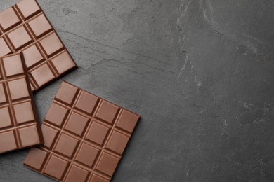 Delicious milk chocolate bars on black table, flat lay. Space for text