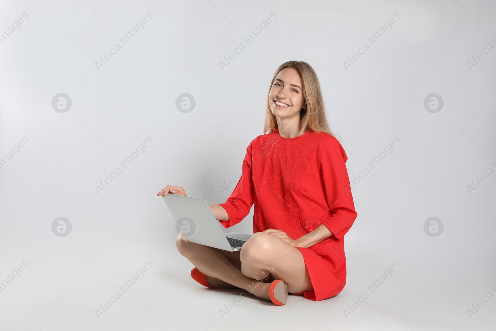 Photo of Young woman with laptop on light grey background