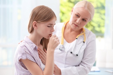 Coughing teenage girl visiting doctor at clinic