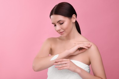 Photo of Beautiful woman with smear of body cream on her arm against pink background