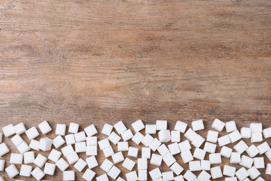 Photo of Refined sugar on wooden table, flat lay. Space for text