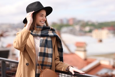 Beautiful woman in warm scarf and hat outdoors, space for text