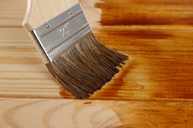 Photo of Applying wood stain on wooden surface, closeup